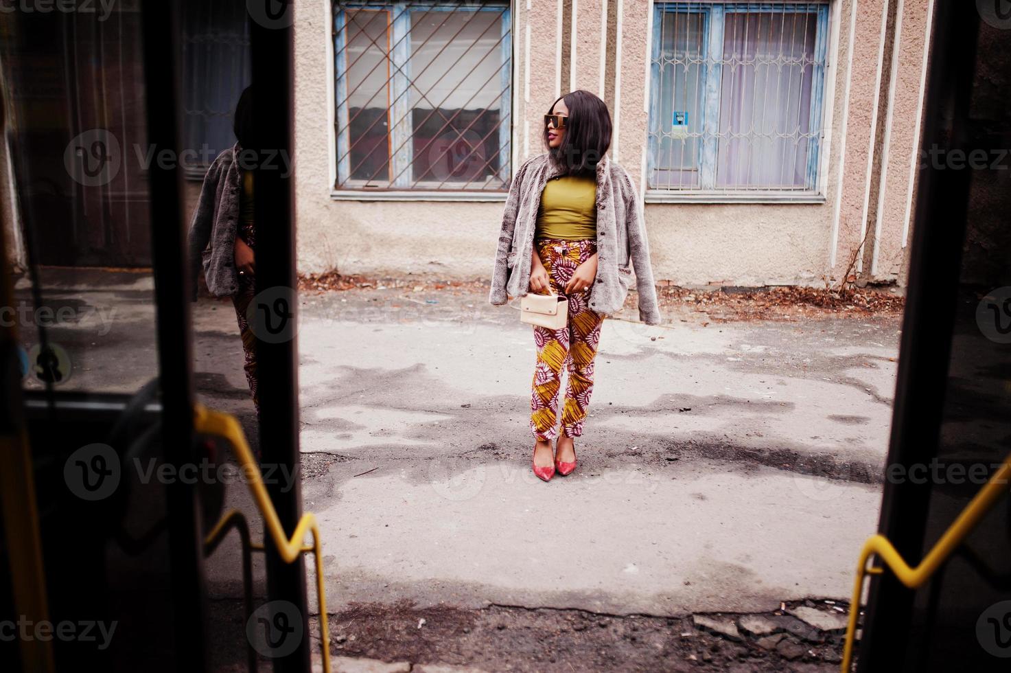 jovem mulher afro-americana elegante em óculos de sol modernos andando de ônibus. foto