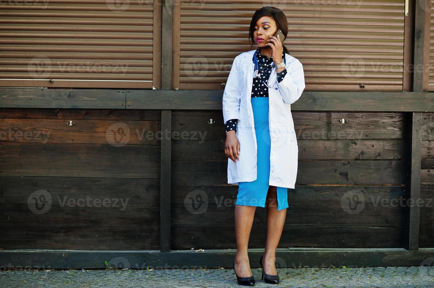 médico americano africano fêmea com estetoscópio falando no telefone. foto