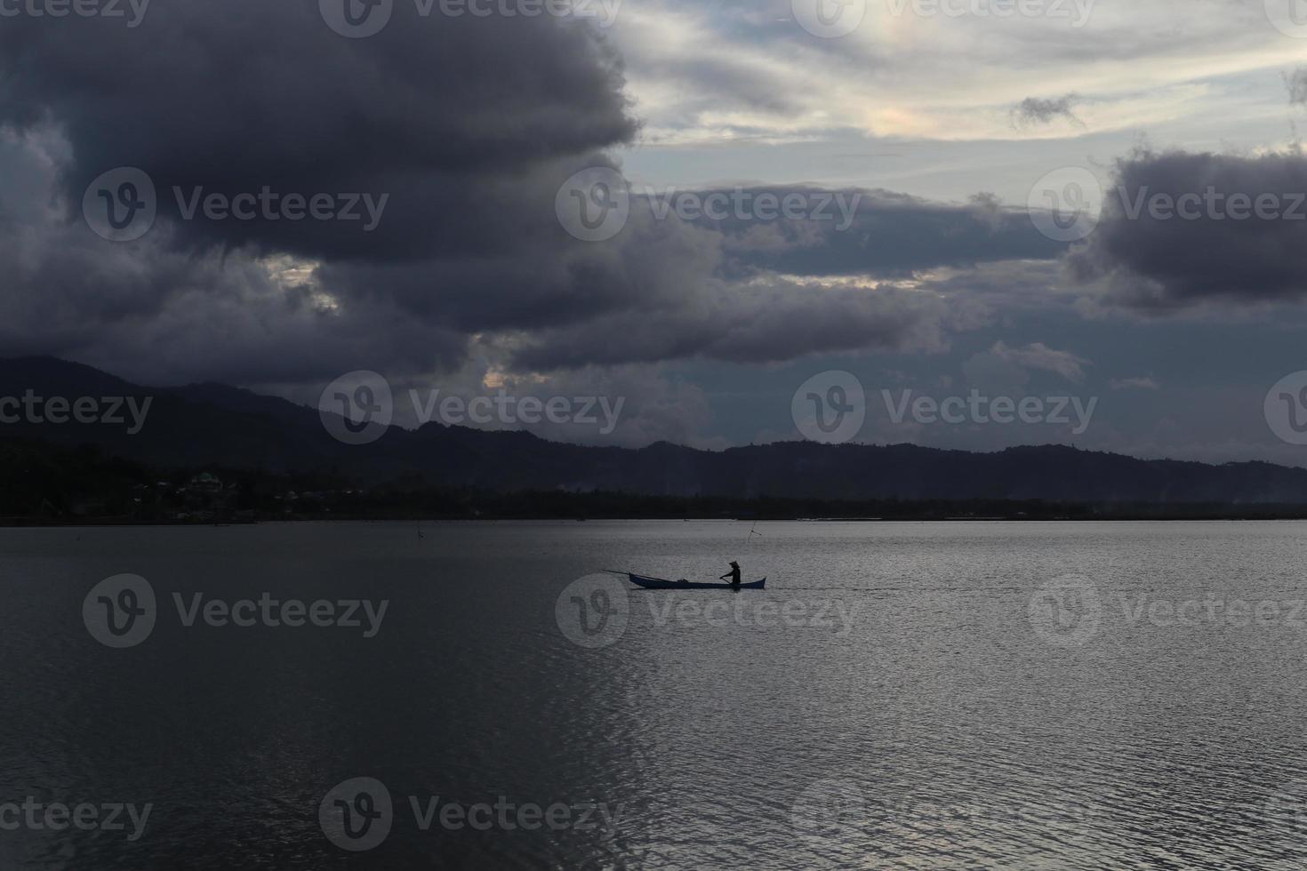 silhueta de pescador em seu barco foto