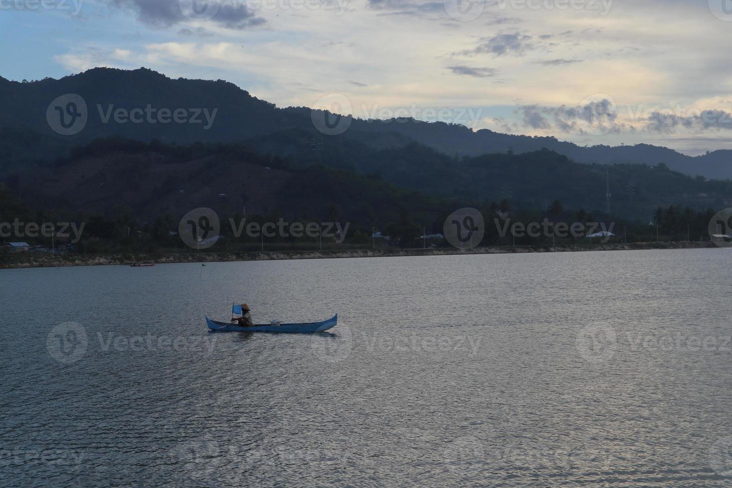 silhueta de pescador em seu barco foto