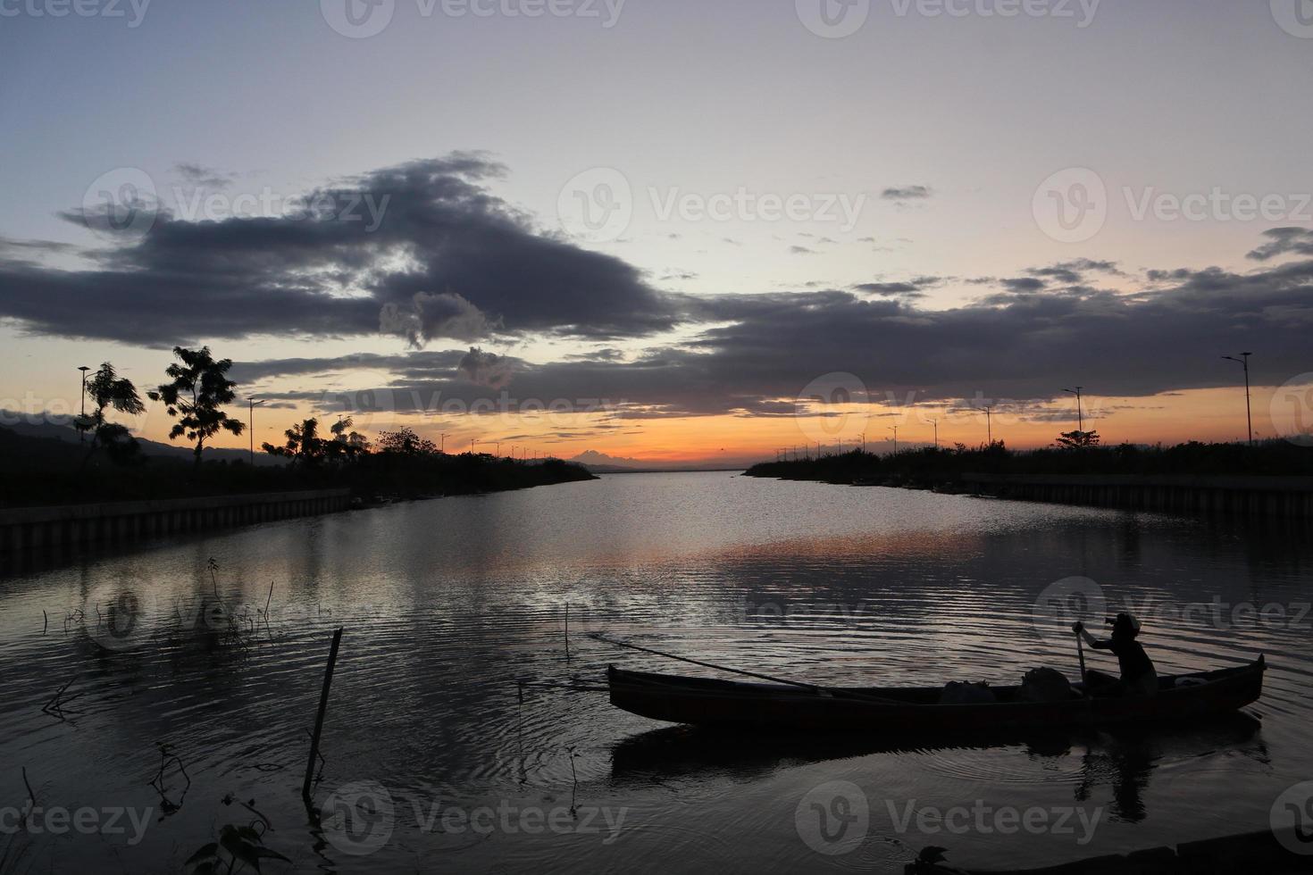 pescador em seu barco ao pôr do sol. barco de pescadores ao pôr do sol foto