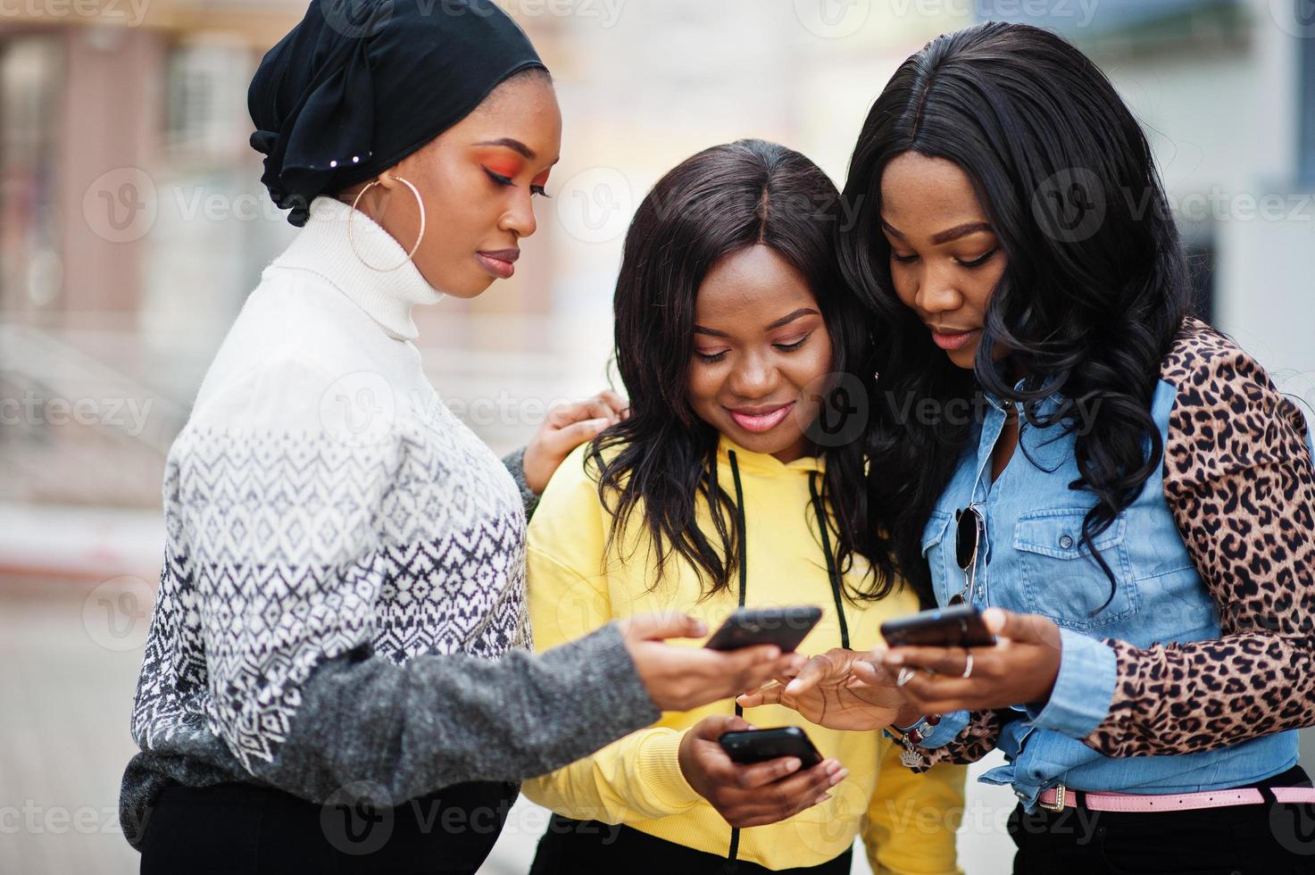 três amigos de mulher afro-americana jovem faculdade com telefones celulares. foto