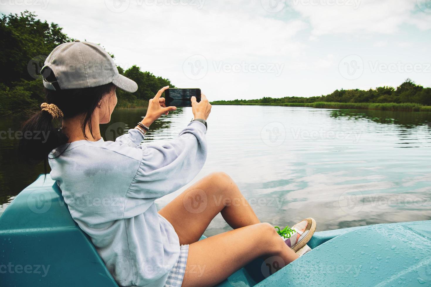 jovem turista caucasiana sente-se no pedalinho e tire fotos do lago e da natureza verde em kolkheti, geórgia