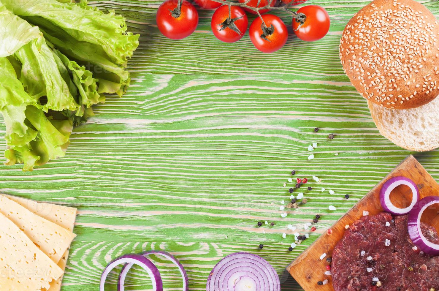 os ingredientes para o hambúrguer em fundo verde de madeira foto