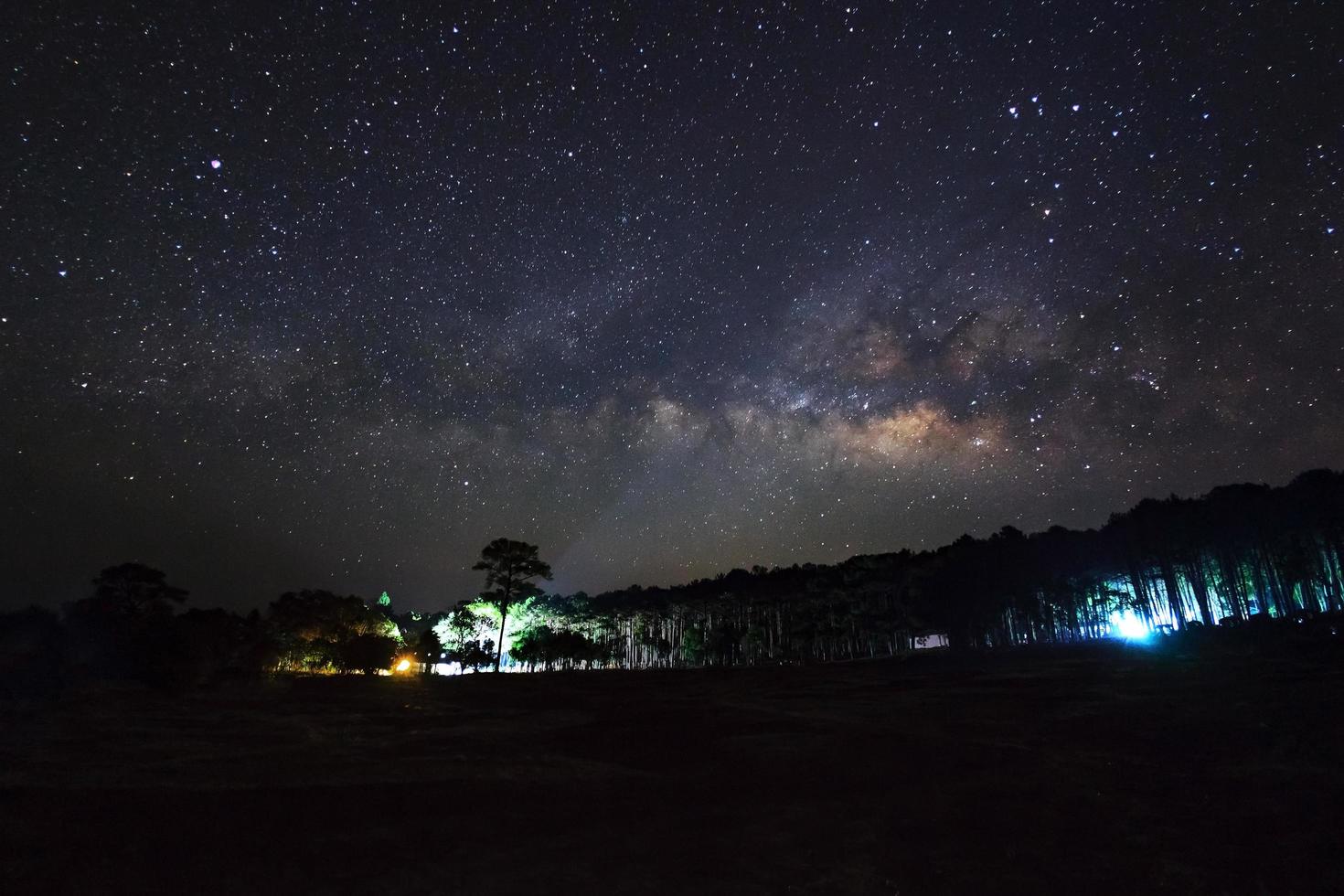 bela galáxia da Via Láctea em um céu noturno e silhueta de árvore, fotografia de longa exposição. com grãos foto