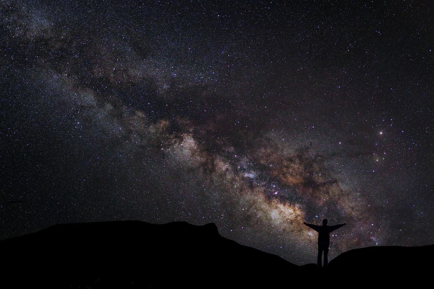 paisagem com via láctea, céu noturno com estrelas e silhueta de um homem feliz em pé na montanha, fotografia de longa exposição, com grãos foto