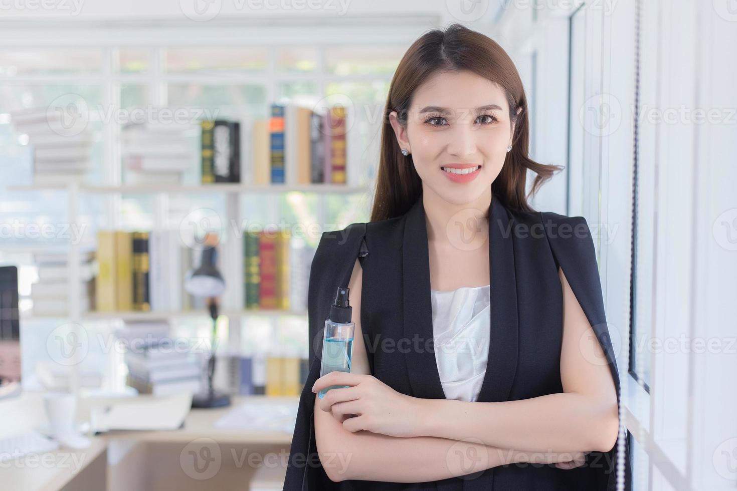 uma mulher confiante com cabelo comprido sorrindo e segurando uma garrafa de álcool spray foto