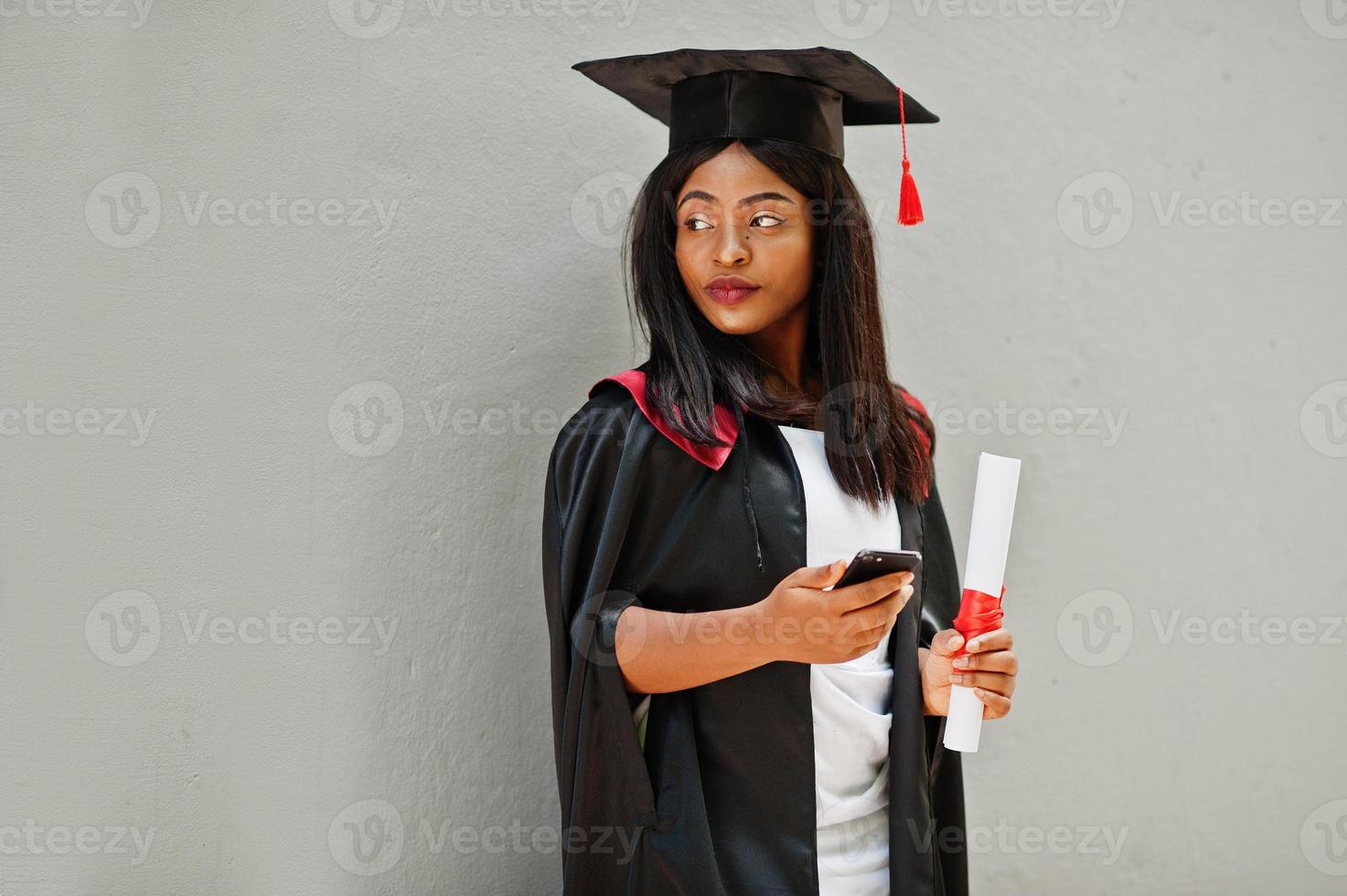 jovem estudante afro-americana com diploma e poses de telefone celular ao ar livre. foto