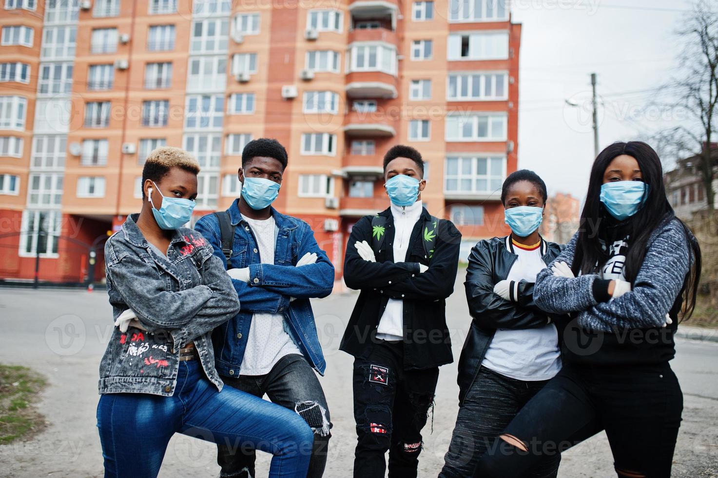 grupo de amigos adolescentes africanos contra a rua vazia com construção usando máscaras médicas protegem contra infecções e doenças quarentena de vírus coronavírus. foto