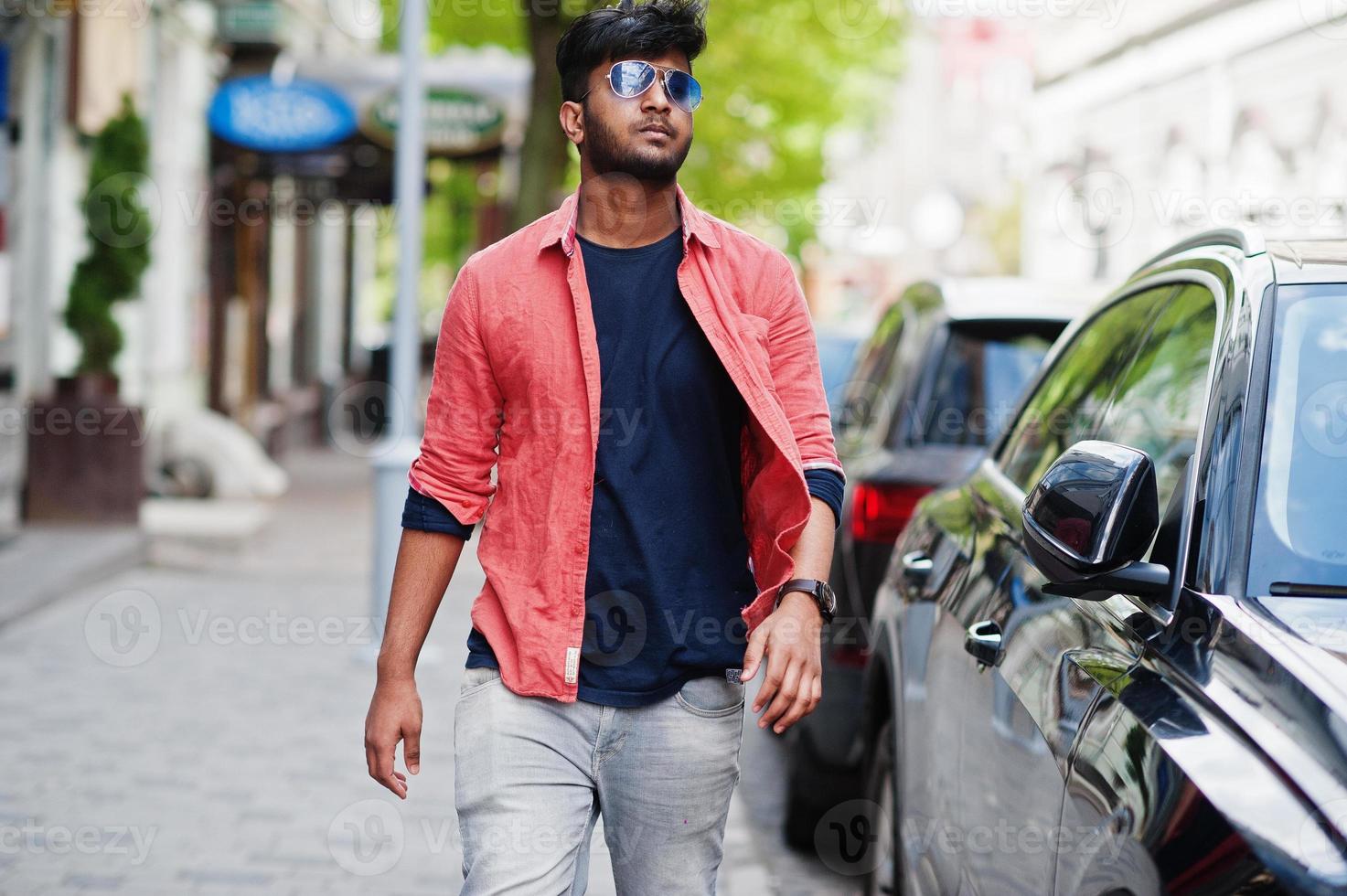 retrato de modelo jovem indiano elegante pose na rua em óculos de sol contra o carro. foto