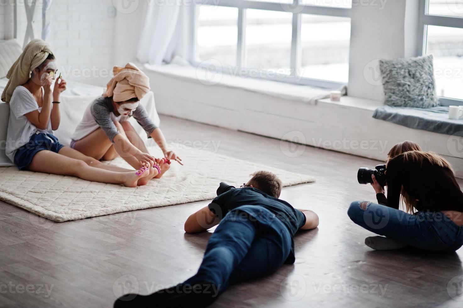 a equipe de dois fotógrafos fotografando garotas gêmeas de estúdio enquanto elas fazem seu próprio creme de máscaras. fotógrafo profissional no trabalho. foto