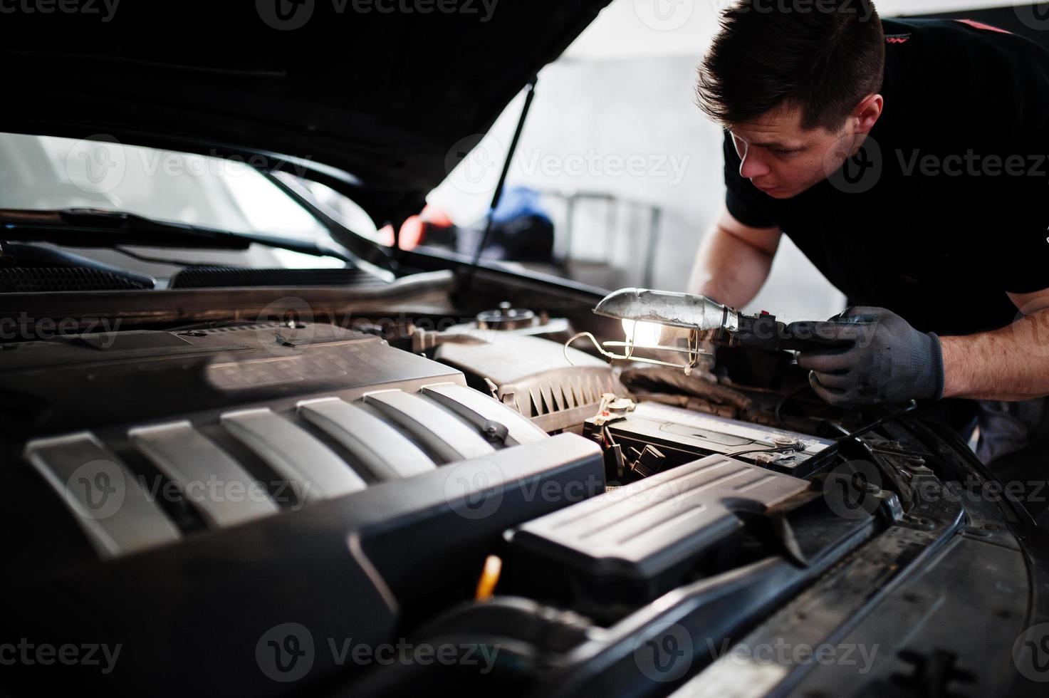 tema de reparação e manutenção de automóveis. mecânico de uniforme trabalhando em auto serviço, verificando o motor. foto