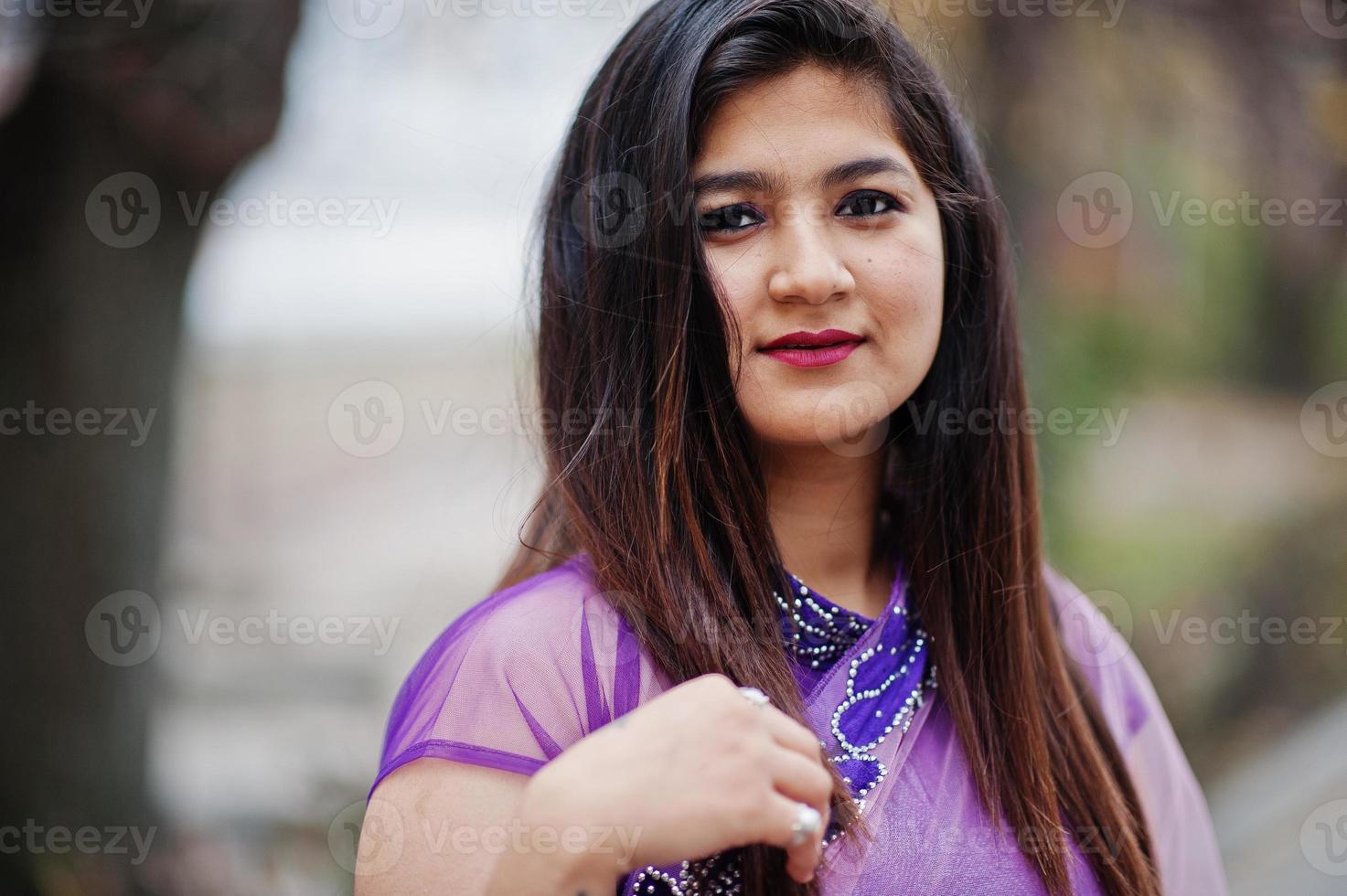 Feche o retrato da menina hindu indiana no tradicional saree violeta posado na rua. foto