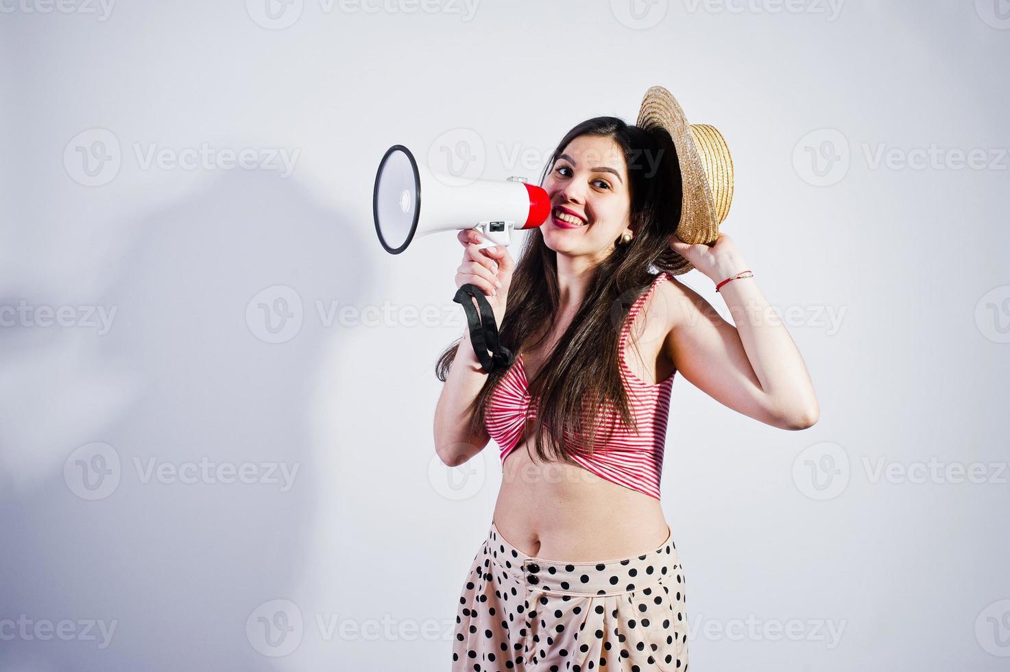 retrato de uma linda jovem em traje de banho e chapéu fala em megafone no estúdio. foto