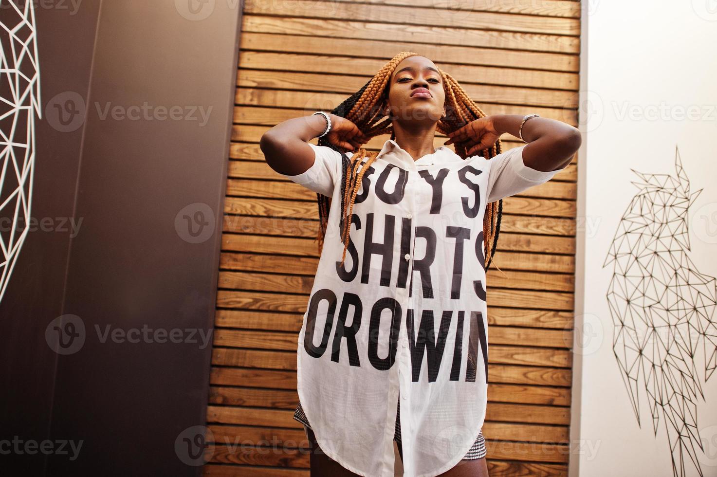 linda mulher africana em roupas casuais elegantes posando contra a parede de asas de anjo. ela movendo seus dreadlocks de cabelo. foto