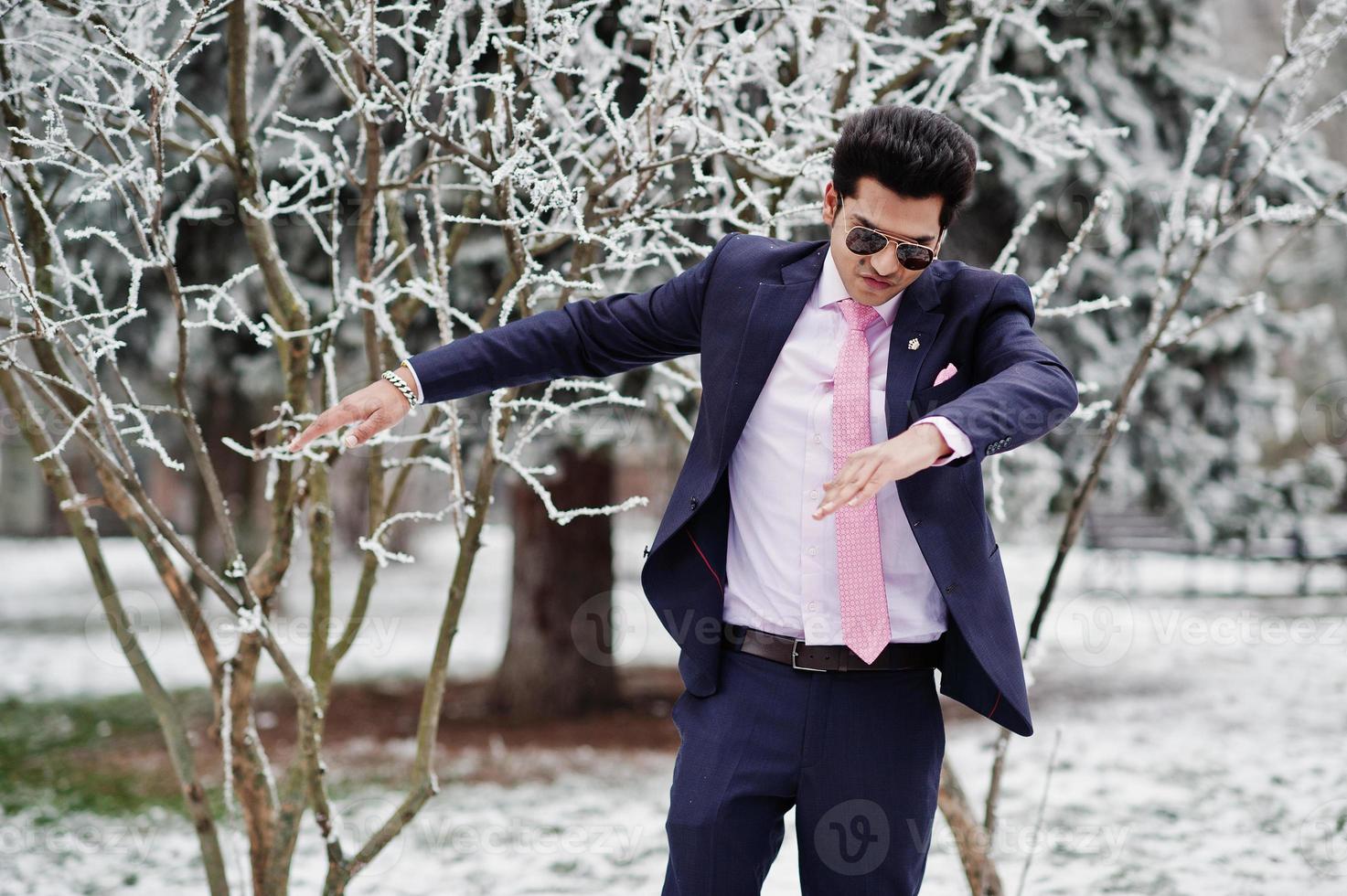 elegante modelo de homem macho indiano de terno e gravata rosa, óculos de sol posados em dia de inverno mostra dab. foto