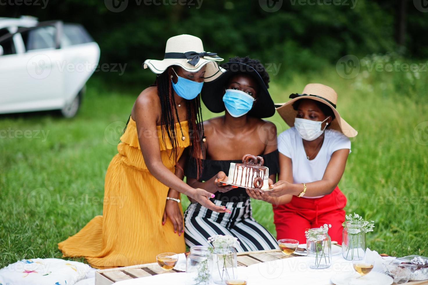 grupo de meninas afro-americanas com máscaras faciais comemorando festa de aniversário ao ar livre com decoração durante a pandemia de coronavírus. foto