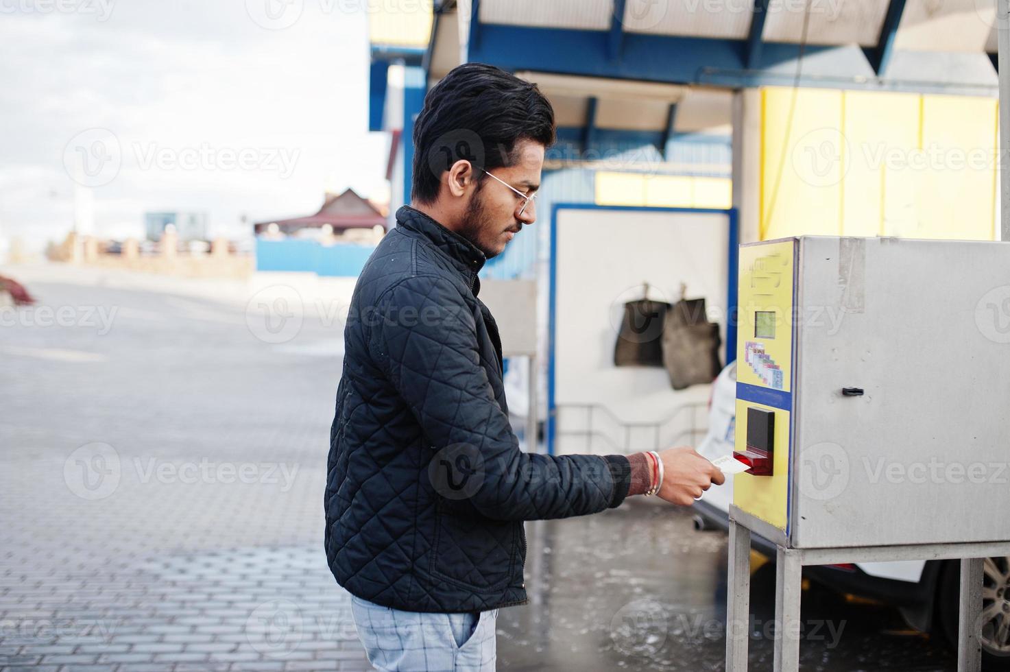 homem do sul da Ásia ou homem indiano lavando seu transporte branco na lavagem de carros. ele colocando dinheiro no caixa eletrônico. foto