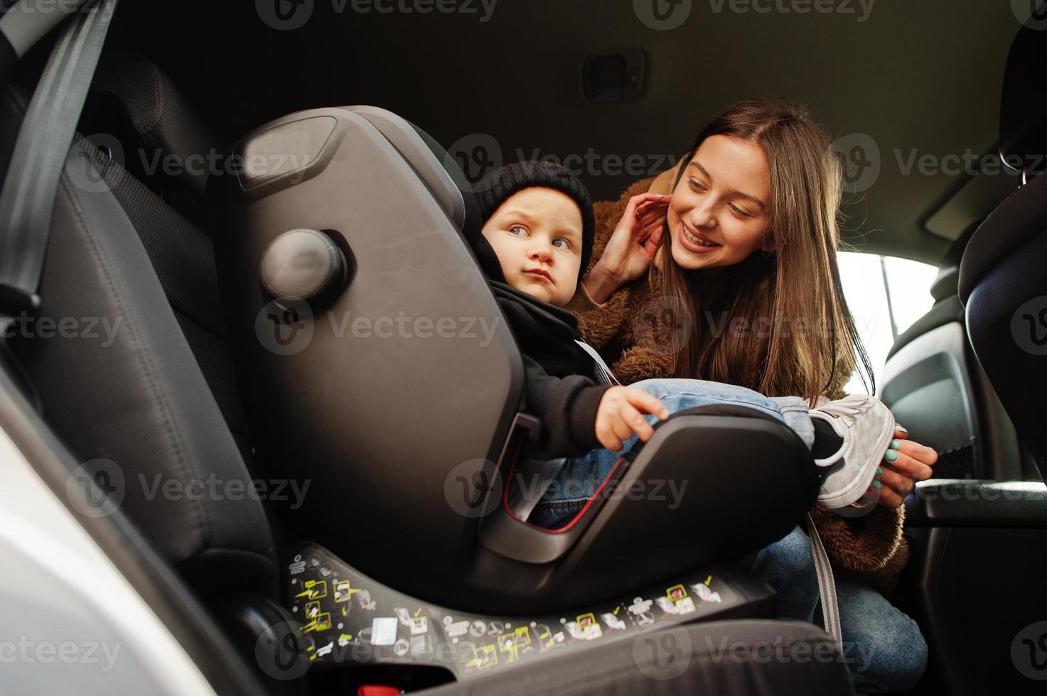 jovem mãe e filho no carro. assento de bebê na cadeira. conceito de condução de segurança. foto
