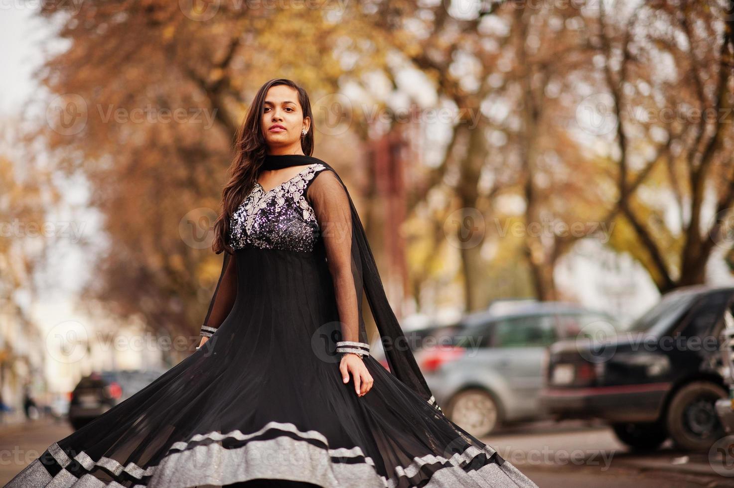 menina bonita indiana no vestido preto saree posou ao ar livre na rua outono. foto