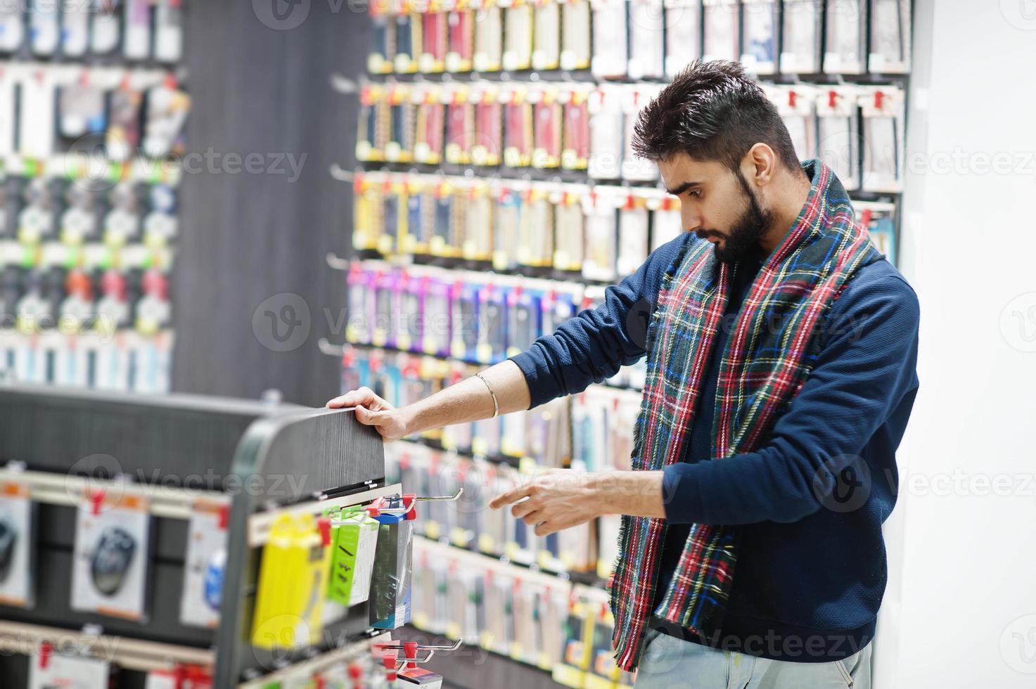 comprador de cliente homem indiano na loja de celulares escolhe uma capa para seu smartphone. conceito de povos e tecnologias do sul da Ásia. loja de celulares. foto