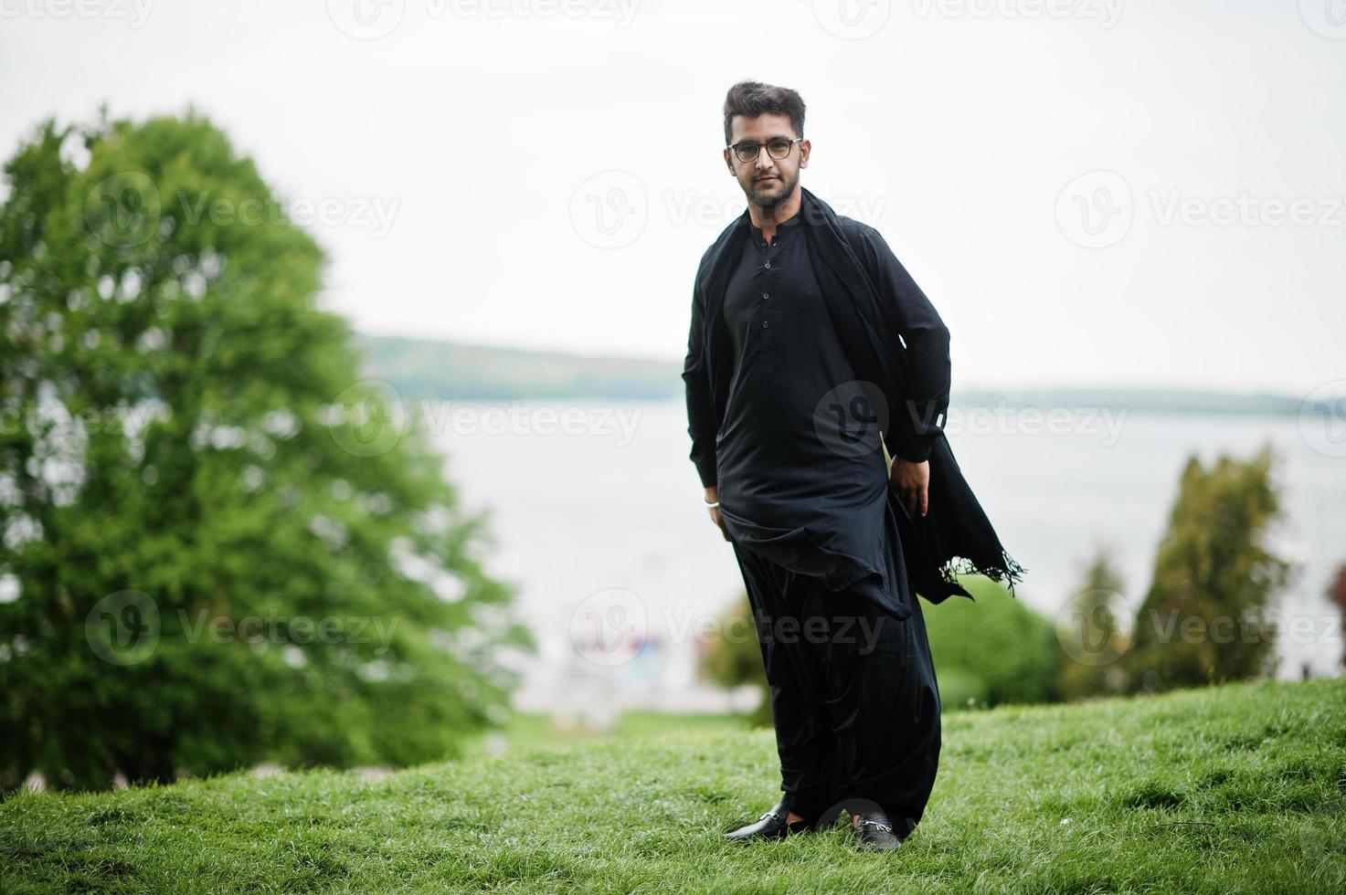 homem de bangladesh paquistanês usa roupas tradicionais pretas e óculos posam ao ar livre. foto