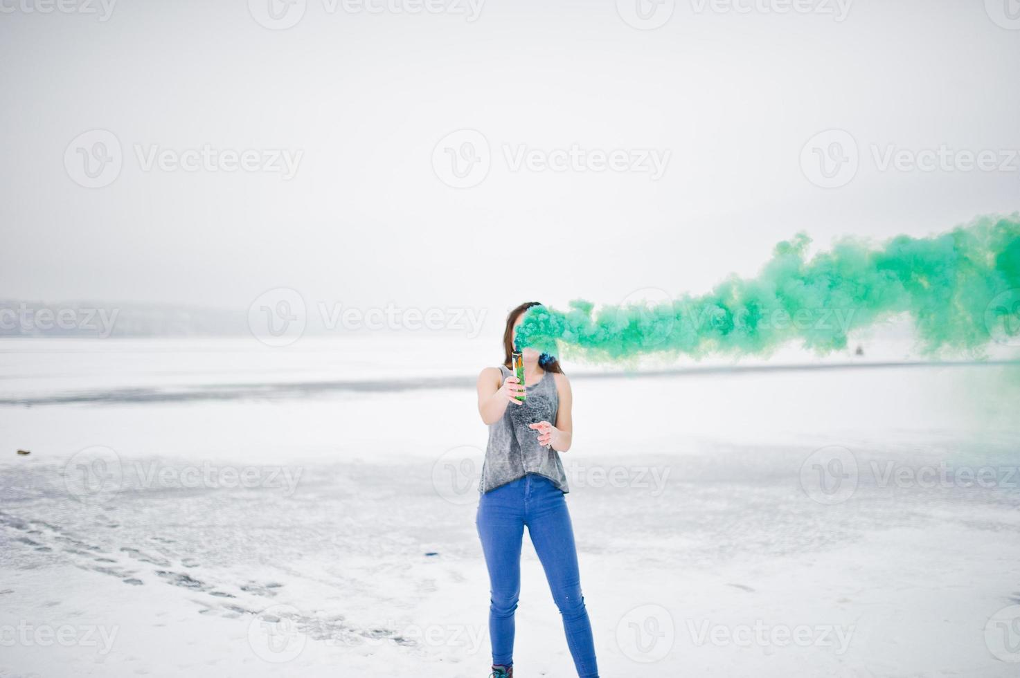 jovem com bomba de fumaça de cor verde na mão em dia de inverno. foto