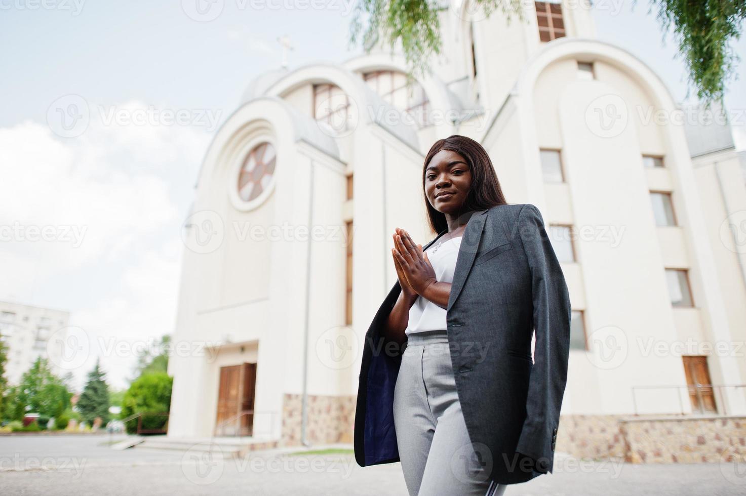 mulher afro-americana ao ar livre contra a igreja e reza a Deus. conceito de fé, espiritualidade e religião. foto