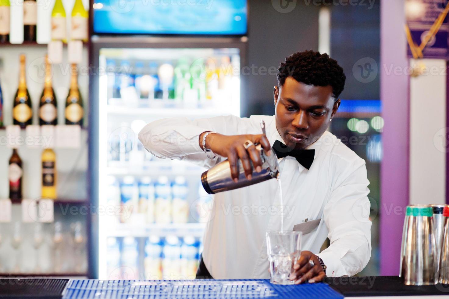 barman americano africano no bar com shaker. preparação de bebidas alcoólicas. foto