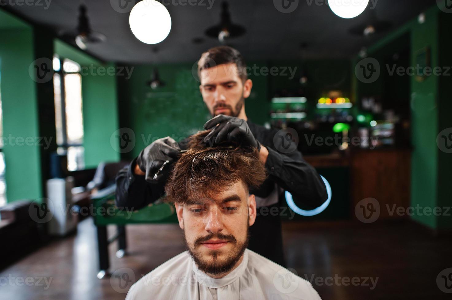 homem barbudo bonito na barbearia, barbeiro no trabalho. foto