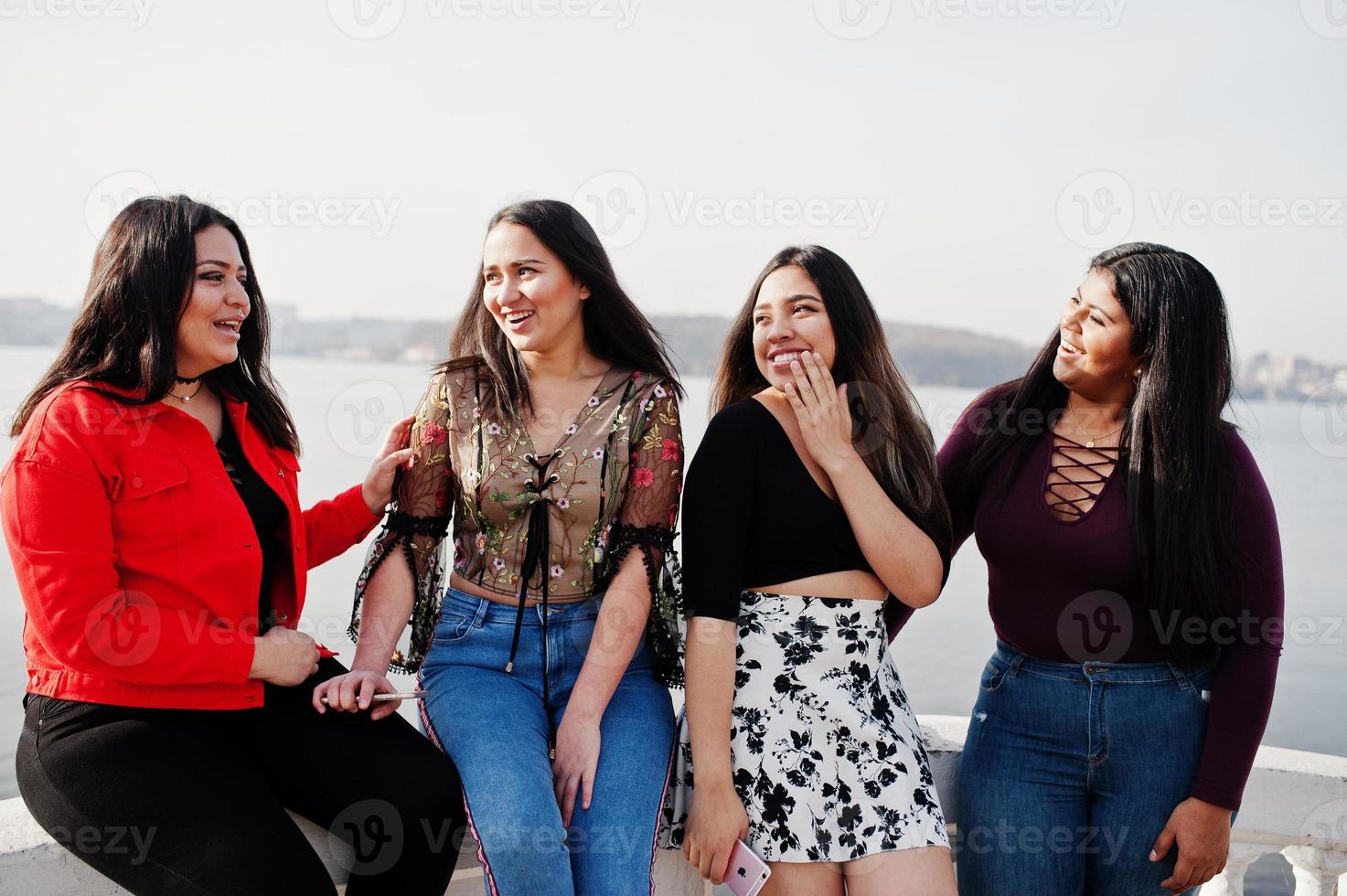 grupo de quatro meninas latinas felizes e bonitas do Equador posou contra o lado do lago. foto