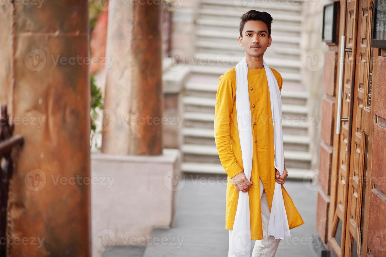 homem elegante indiano em roupas tradicionais amarelas com lenço branco posou ao ar livre. foto