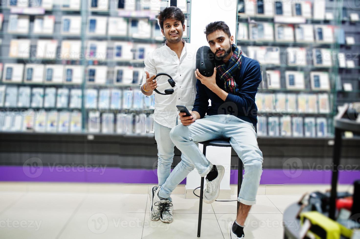 dois índios mans comprador do cliente na loja de telefonia móvel com fones de ouvido e alto-falante sem fio ouvindo música. conceito de povos e tecnologias do sul da Ásia. loja de celulares. foto