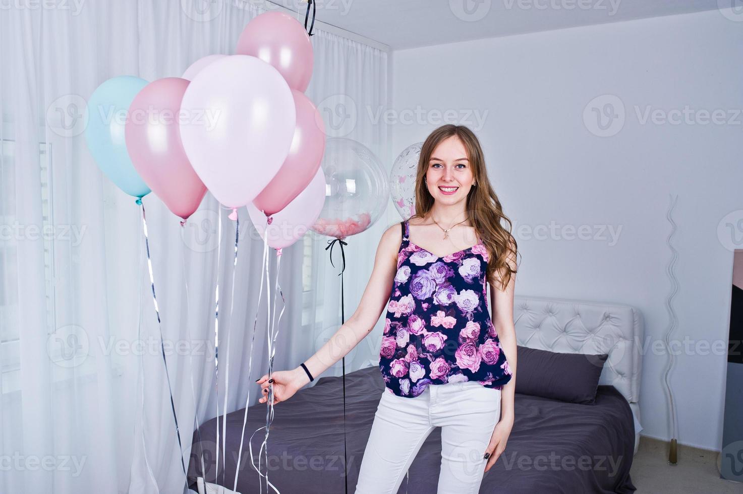 garota feliz com balões coloridos na cama no quarto. comemorando o tema do aniversário. foto