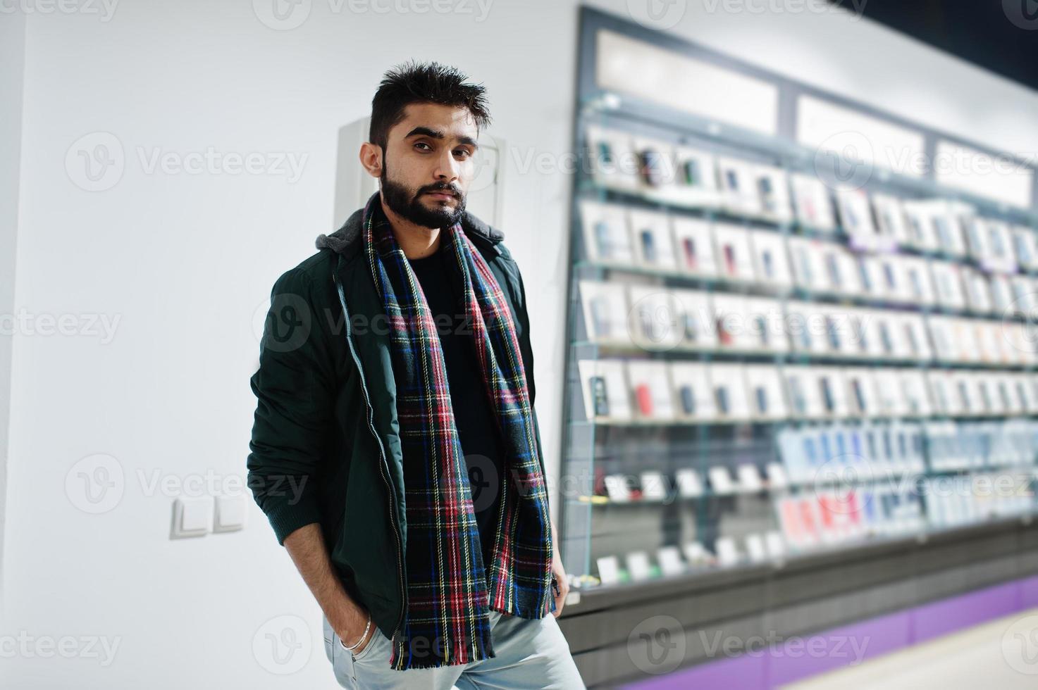 comprador de cliente de homem de barba indiana na jaqueta na loja de telefones celulares. conceito de povos e tecnologias do sul da Ásia. loja de celulares. foto