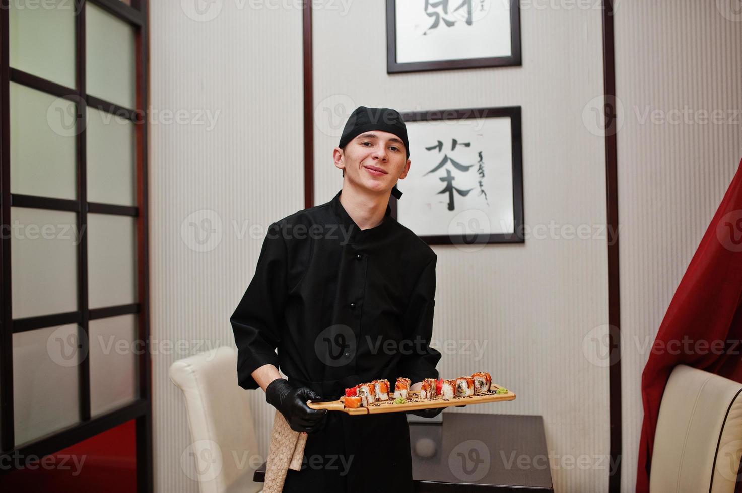 chef profissional veste de preto com sushi e pãezinhos em um restaurante de comida tradicional japonesa. foto