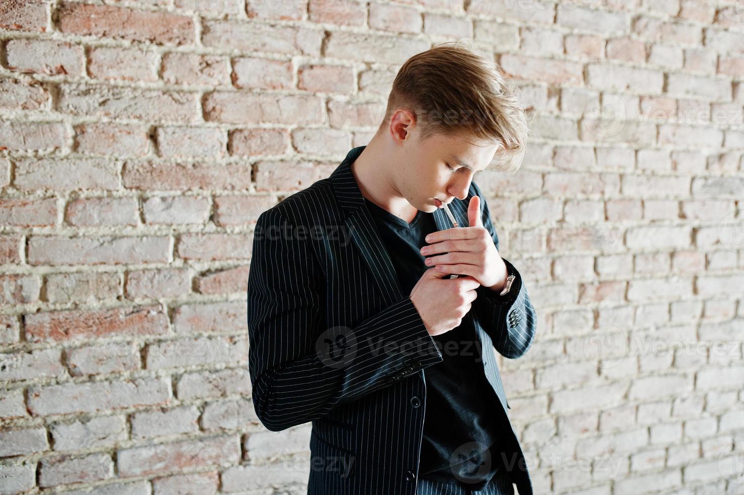 jovem macho vestindo jaqueta elegante blac fumando cigarro nas ruas. foto