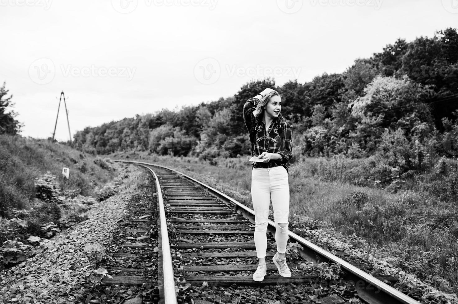 retrato de uma menina bonita loira na camisa tartan andando na ferrovia com mapa nas mãos dela. foto