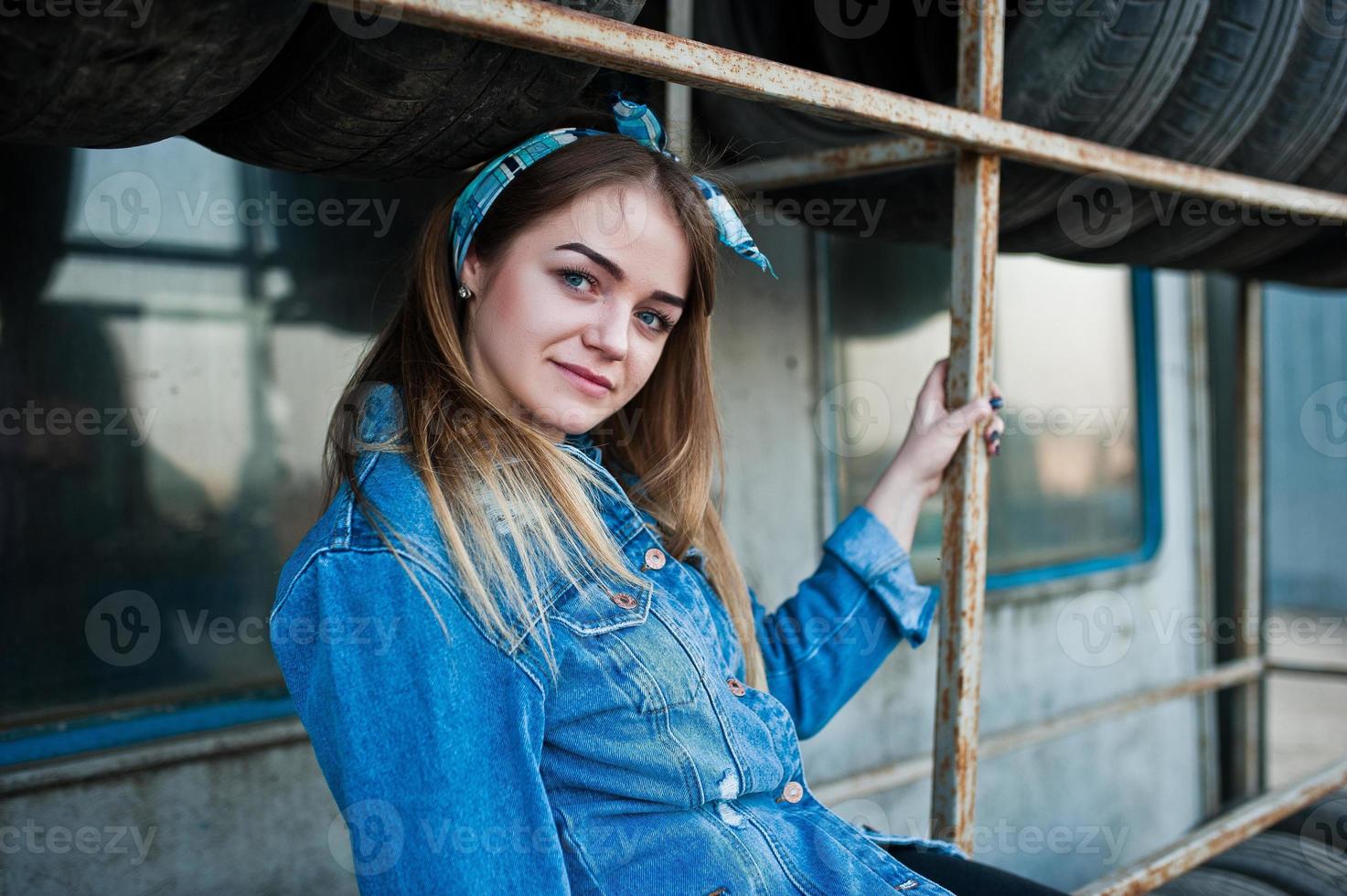 garota jovem hippie na jaqueta jeans e lenço na cabeça na zona de montagem do pneu. foto