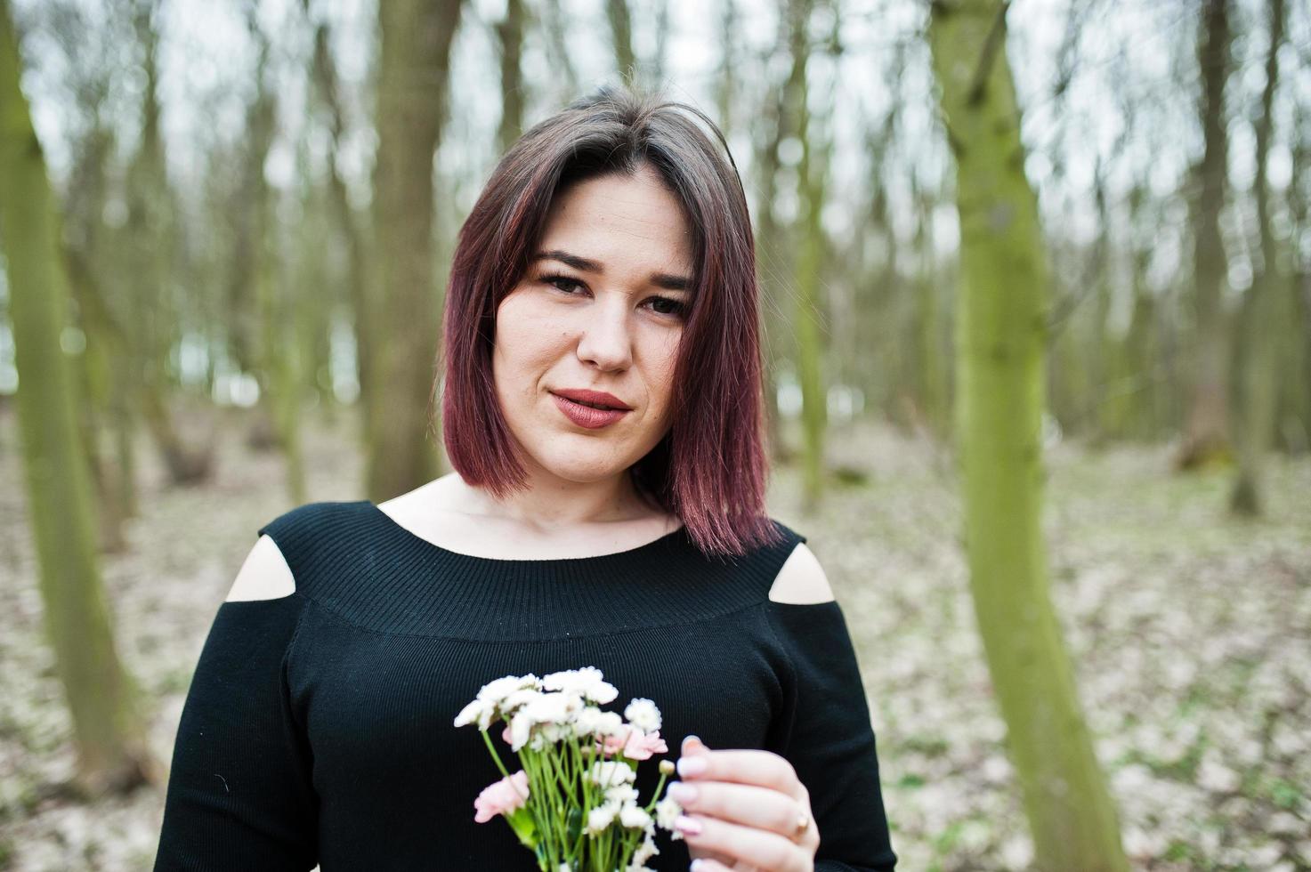 retrato de menina morena de vestido preto em madeira de primavera. foto