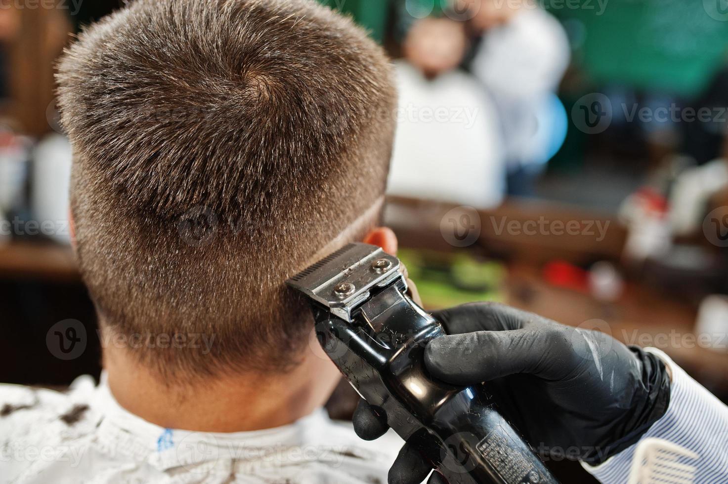 homem barbudo bonito na barbearia, barbeiro no trabalho. feche a nuca. foto