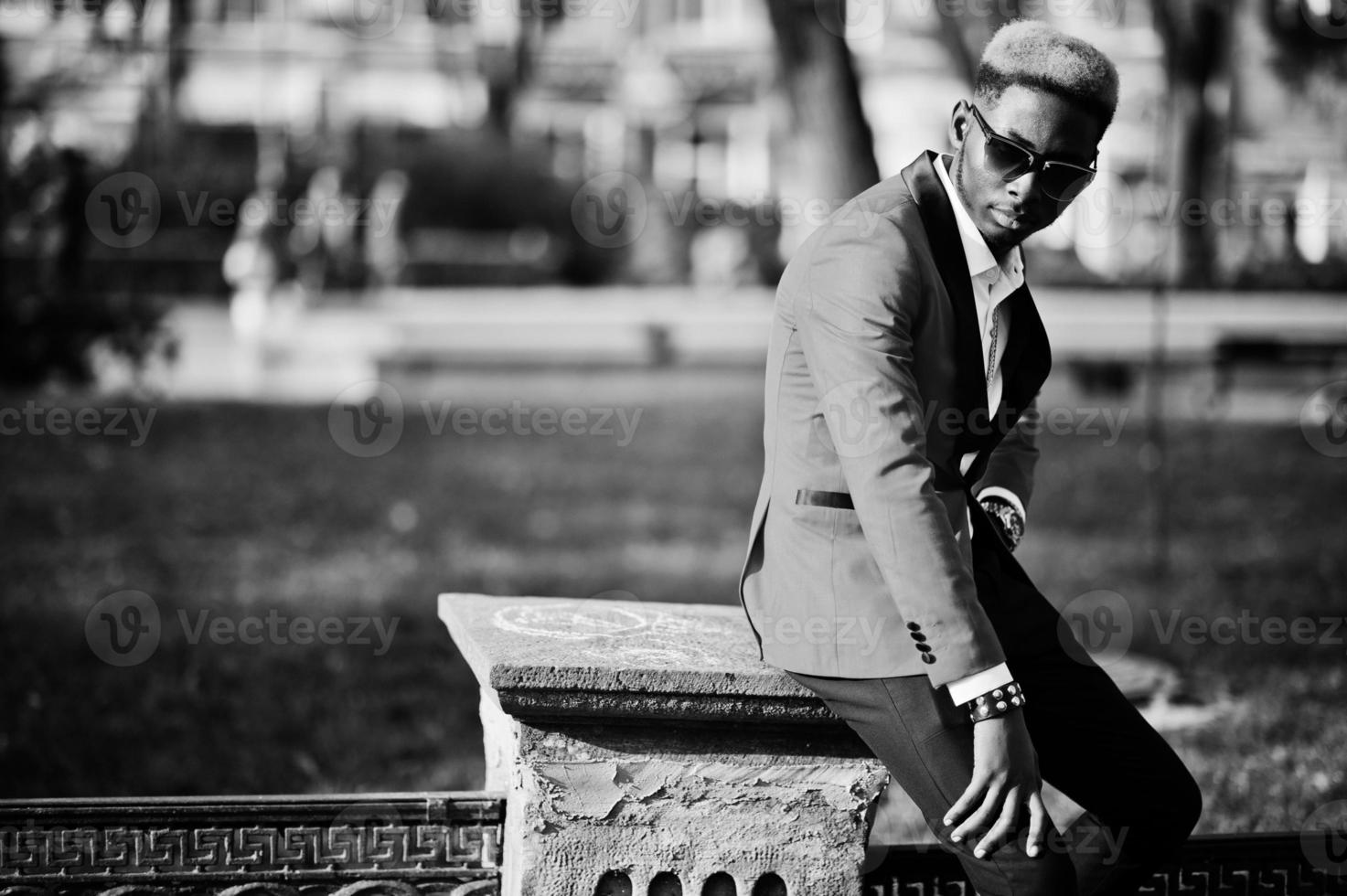 modelo de homem afro-americano de moda no terno vermelho, com destaques de cabelo e bolsa posou na rua. foto