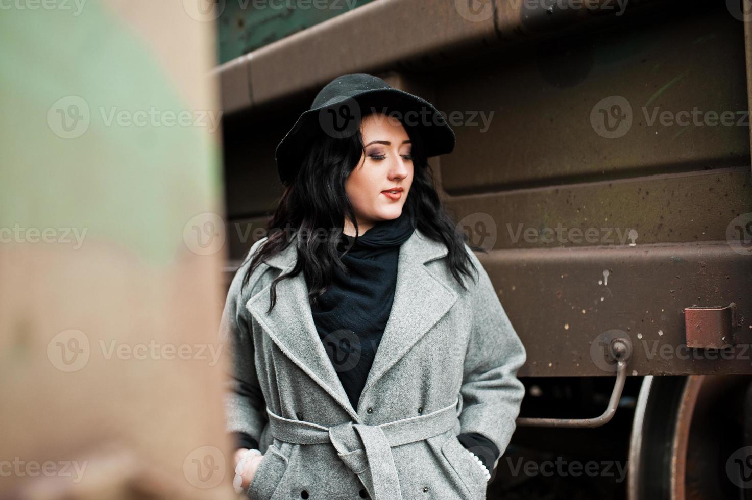 menina morena de casaco cinza com chapéu na estação ferroviária. foto