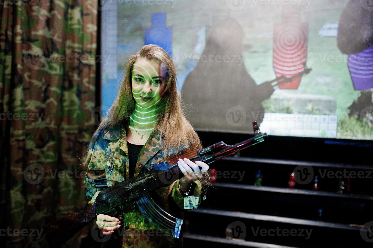 menina com metralhadora em mãos no campo de tiro. foto