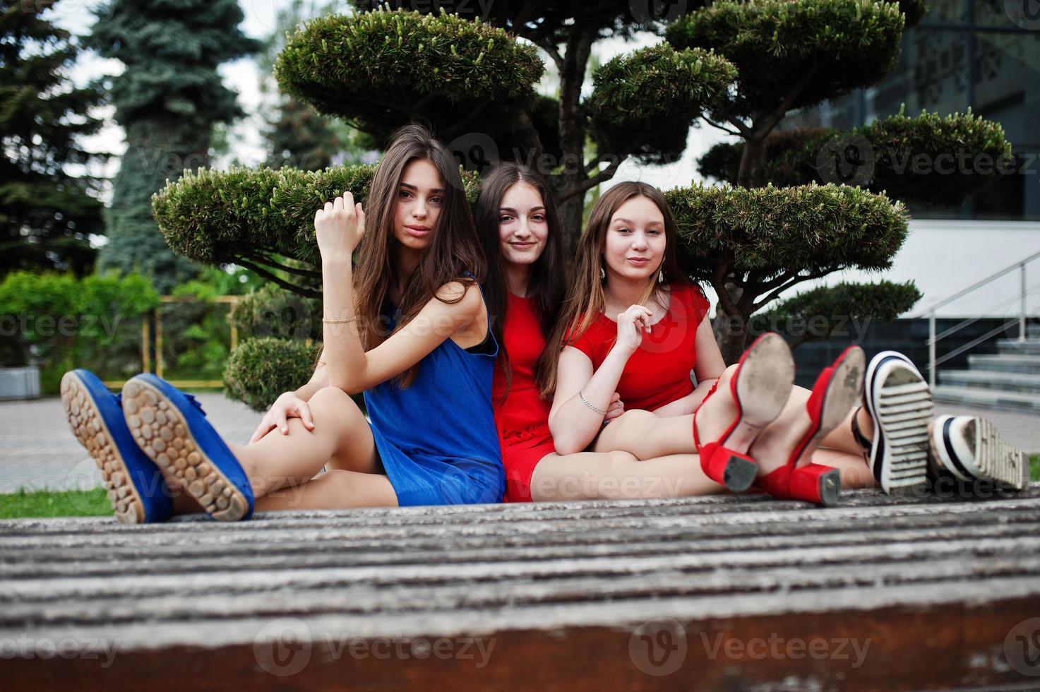 menina de três adolescentes em vestidos azuis e vermelhos posou ao ar livre. foto