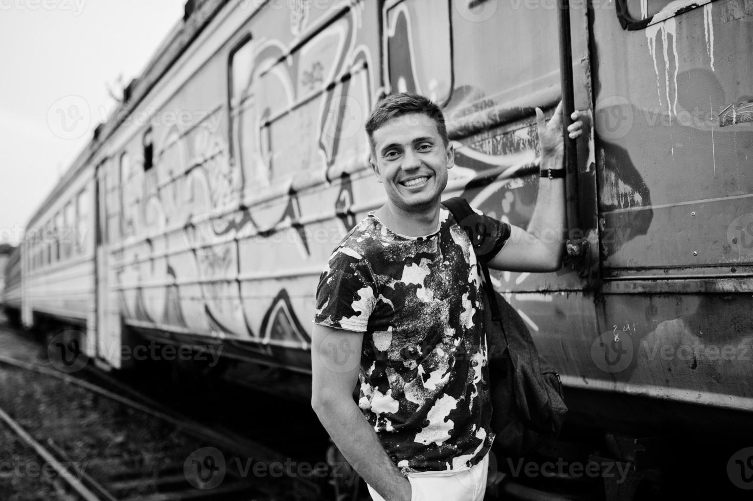 retrato de estilo de vida de homem bonito com mochila posando na estação de trem. foto