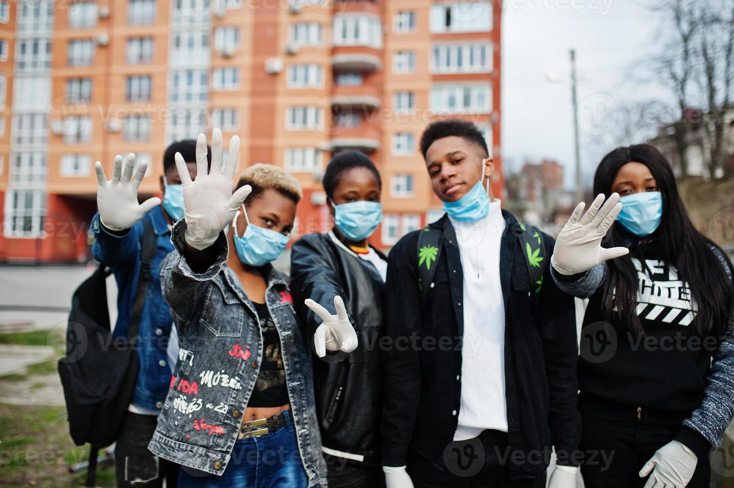 grupo de amigos adolescentes africanos contra a rua vazia com construção usando máscaras médicas protegem contra infecções e doenças quarentena de vírus coronavírus. foto