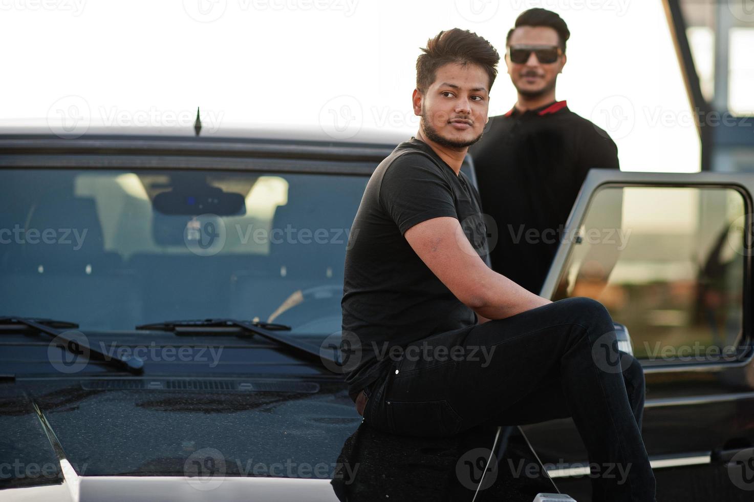 dois irmãos asiáticos vestem todo preto posando perto do carro suv. foto