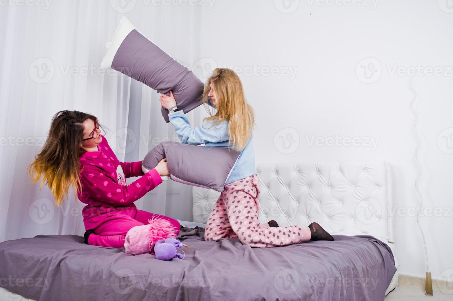 duas amigas garotas de pijama se divertindo na cama no quarto. foto