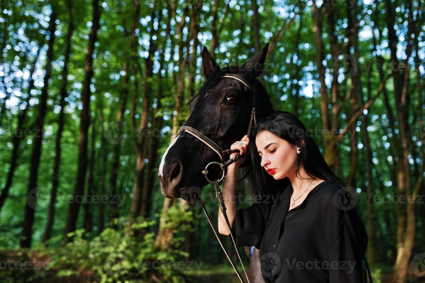 garota mística veste de preto com cavalo em madeira. foto